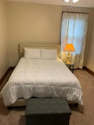 a bedroom with a bed and a lamp and a window at A2 Executive City View apartment perfect for traveling professionals in Norwood