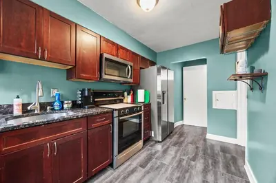 a kitchen with wooden cabinets and a stainless steel refrigerator at Heated, Cozy 3BR Perfect for Winter Getaways in Columbus