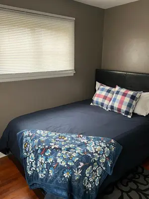 a bed with a blue comforter and a pillow at Relaxing 4BR Holiday Retreat Large, Cozy & Close to Airport in Columbus