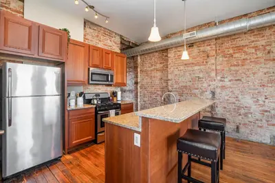 a kitchen with a stainless steel refrigerator and wooden cabinets at The Reserve - Heart of OTR 2 Bed Suite w/Views in Cincinnati