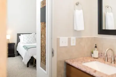 a bathroom with a sink and a bedroom with a bed at The Reserve - Heart of OTR 2 Bed Suite w/Views in Cincinnati