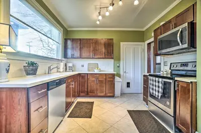 a kitchen with wooden cabinets and a large window at Charming and Family-Friendly Zanesville Home! in Zanesville