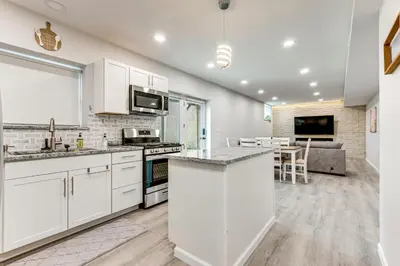 a kitchen with white cabinets and a living room at Renovated Logan Home with Pond and Fire Pit in Logan