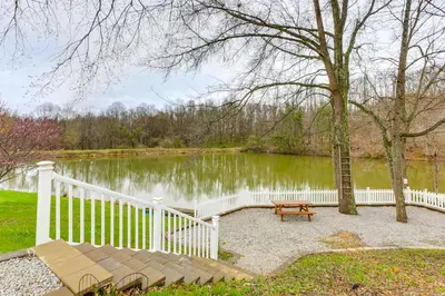 a white fence and a bench next to a pond at Renovated Logan Home with Pond and Fire Pit in Logan