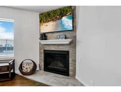 a living room with a fireplace with a picture of a beach at Housepitality - Little River Trails in Mason
