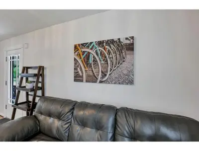 a leather couch in a living room with a painting on the wall at Housepitality - Little River Trails in Mason