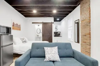 a living room with a blue couch and a bed at Housepitality - The Reichstag Suite - Modern in Columbus