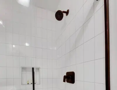 a shower with white tiled walls and a shower head at Housepitality - The Reichstag Suite - Modern in Columbus