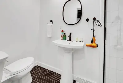 a white bathroom with a sink and a mirror at Housepitality - The Reichstag Suite - Modern in Columbus