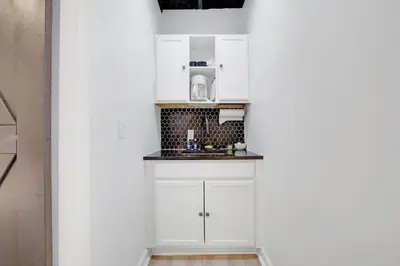 a small kitchen with white cabinets and a sink at Housepitality - The Reichstag Suite - Modern in Columbus