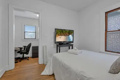 a bedroom with a bed and a desk with a television at Housepitality - The Maynard Manor in Columbus