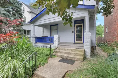 a white house with a blue door and stairs at Housepitality - The Maynard Manor in Columbus