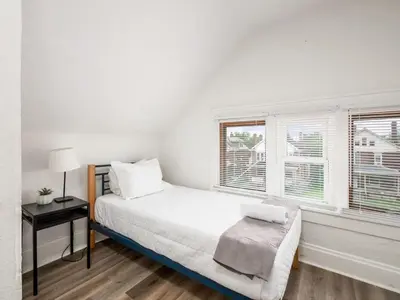 a white bedroom with a bed and two windows at Large 5 Bedroom House Next to OSU, Sleeps 16 in Columbus