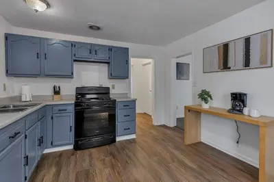 a kitchen with blue cabinets and a black stove at Housepitality - The Southside Ranch in Columbus