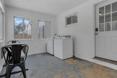 a white laundry room with a chair and a washer and dryer at Housepitality - The Southside Ranch in Columbus