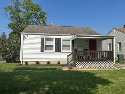 a white house with a porch with a deck at Housepitality- The Bungalow -2 BR in Columbus