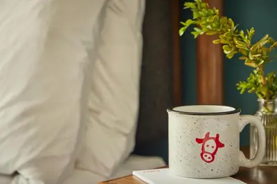a coffee cup sitting on a table next to a bed at The Junto Hotel in Columbus