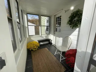 a porch with a chair and a table and flowers at New! Cozy 4-bedroom w/ free parking. Dogs welcome! in Berea