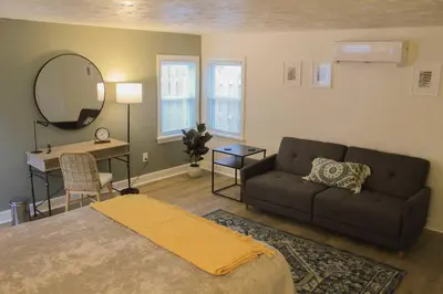 a bedroom with a couch and a table and a mirror at New 1-bedroom Bungalow! 4 miles to CLE in Berea