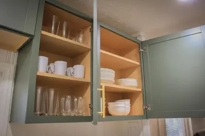 a cabinet with plates and cups and dishes in it at New 1-bedroom Bungalow! 4 miles to CLE in Berea