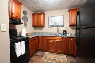 a kitchen with wooden cabinets and a black refrigerator at Extended Stays by Lee House Inn in Maysville