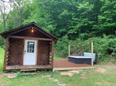 a wooden outhouse with a wooden deck with a white door at Cozy Creekside Cabin in the heart of Hocking Hills in Laurelville
