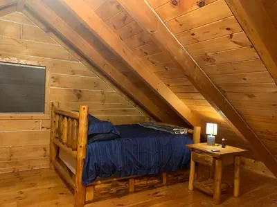 a bedroom in a log cabin with a bed and a table at Cozy Creekside Cabin in the heart of Hocking Hills in Laurelville
