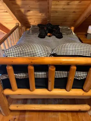 a bed in a wooden room with at Cozy Creekside Cabin in the heart of Hocking Hills in Laurelville
