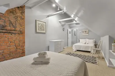 a white bedroom with a white bed and a brick wall at Housepitality - Harrison Mansion - Great Location in Columbus