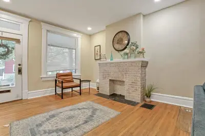 a living room with a fireplace and a clock on the wall at Housepitality - Harrison Mansion - Great Location in Columbus