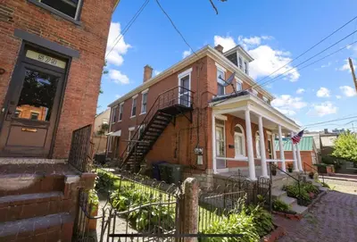 an old brick house with a staircase in front of it at Housepitality - The City Gateway in Columbus