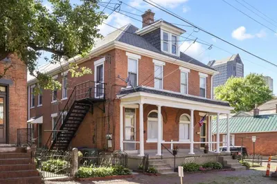 a red brick house with a staircase in front of it at Housepitality - The City Gateway in Columbus