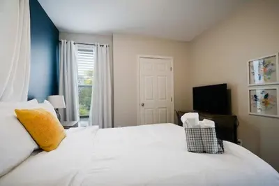 a bedroom with a large white bed and a television at Housepitality - The Lilley Pad - Near Downtown in Columbus
