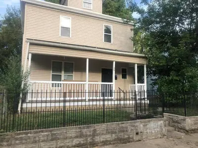 a house with a fence in front of it at Housepitality - Franklinton Manor - Spacious in Columbus