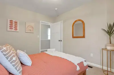 a bedroom with a bed with an orange blanket and a mirror at Housepitality - The Southwestern in Columbus