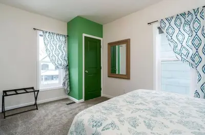 a bedroom with green and white walls and a bed at Housepitality - The Mint Julep House in Columbus