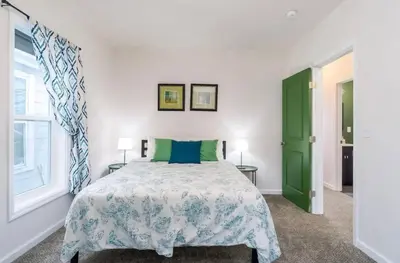 a bedroom with a bed and a green door at Housepitality - The Mint Julep House in Columbus