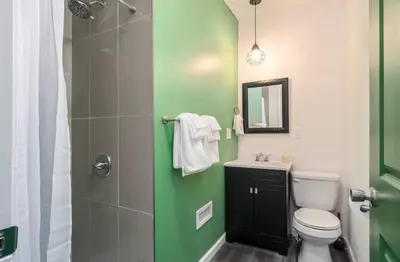 a green and white bathroom with a toilet and a shower at Housepitality - The Mint Julep House in Columbus