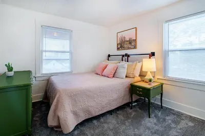 a bedroom with a bed with a lamp and two windows at King Bed, 2 Full Baths, Large Deck, Free Bikes, 2 miles to Downtown & Sports Fieldhouse in Fort Wayne