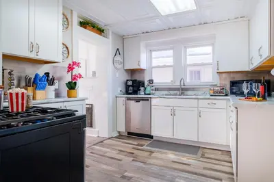 a kitchen with white cabinets and a black stove top oven at King Bed, 2 Full Baths, Large Deck, Free Bikes, 2 miles to Downtown & Sports Fieldhouse in Fort Wayne