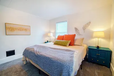 a bedroom with a bed with orange pillows and a window at King Bed, 2 Full Baths, Large Deck, Free Bikes, 2 miles to Downtown & Sports Fieldhouse in Fort Wayne