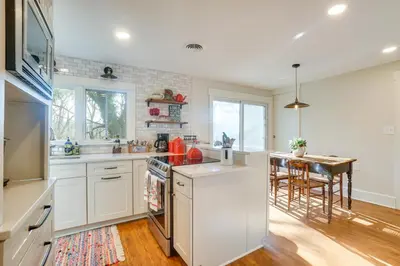 a kitchen with white cabinets and a table in it at The Porch House Located in Historic Village in Granville