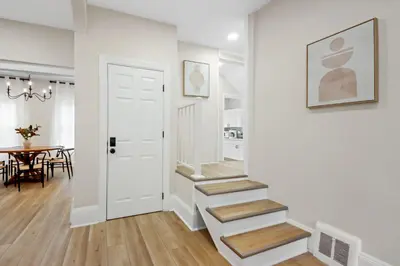 a hallway with stairs and a dining room with a table at The Lakewood Belle: Family Friendly Home 10 minutes to Downtown! in Cleveland