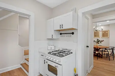 a white kitchen with a stove and a dining room at The Lakewood Belle: Family Friendly Home 10 minutes to Downtown! in Cleveland