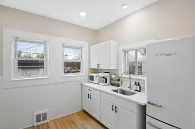 a kitchen with white cabinets and a sink and two windows at The Lakewood Belle: Family Friendly Home 10 minutes to Downtown! in Cleveland