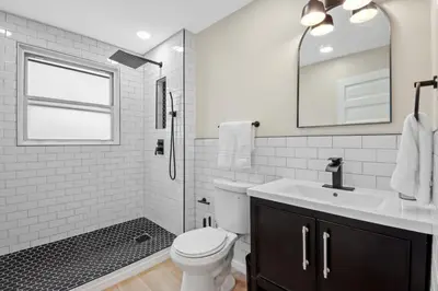 a bathroom with a toilet and a sink and a mirror at The Lakewood Belle: Family Friendly Home 10 minutes to Downtown! in Cleveland