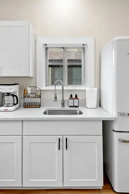 a white kitchen with a sink and a refrigerator at The Lakewood Belle: Family Friendly Home 10 minutes to Downtown! in Cleveland