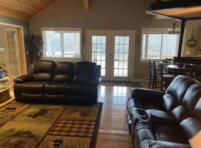 a living room with a leather couch and a table at Lakehouse Hot Tub & Pool close to Ark Encounter in Corinth