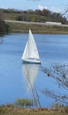 a small white sail boat on a body of water at Lakehouse Hot Tub & Pool close to Ark Encounter in Corinth