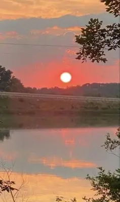 a sunset over a body of water with the sun setting at Lakehouse Hot Tub & Pool close to Ark Encounter in Corinth